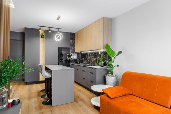 A modern kitchen with a bar area, grey cabinets, and a wooden accent wall.
