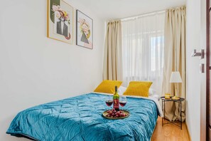 A bedroom with a bed, a nightstand, a lamp, and two paintings on the wall.