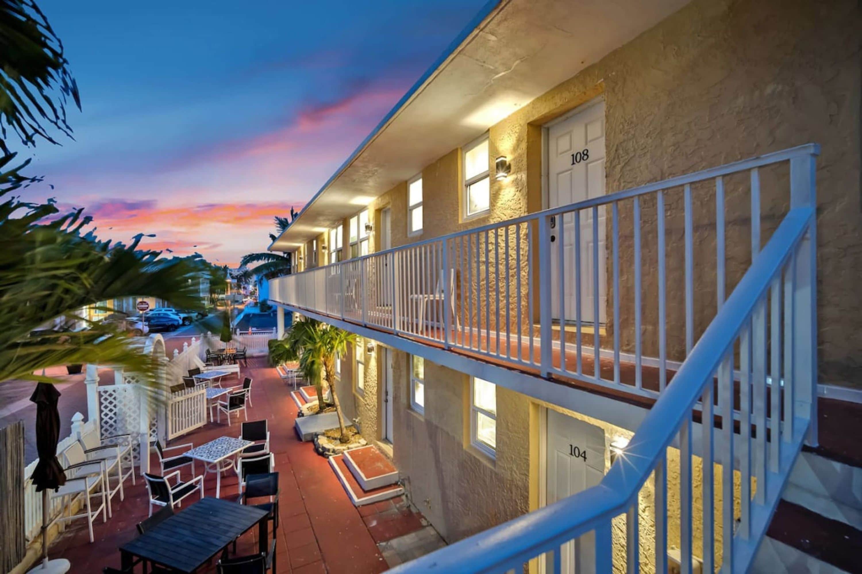 A hotel with a balcony, outdoor seating, and a view of the street.