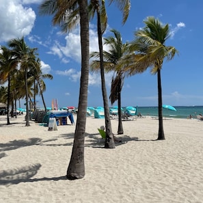 Una playa con palmeras, sombrillas y sillas de playa.