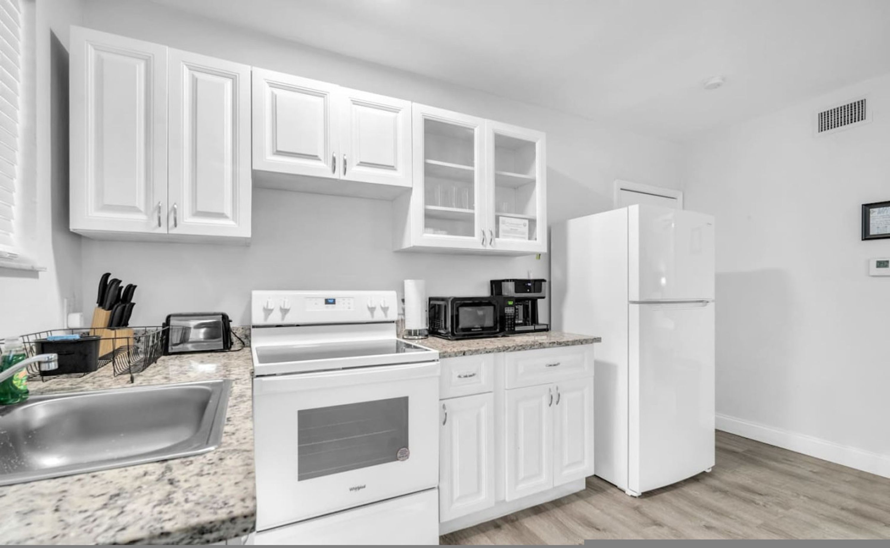 A kitchen with white cabinets, a white refrigerator, a microwave, and a stove.