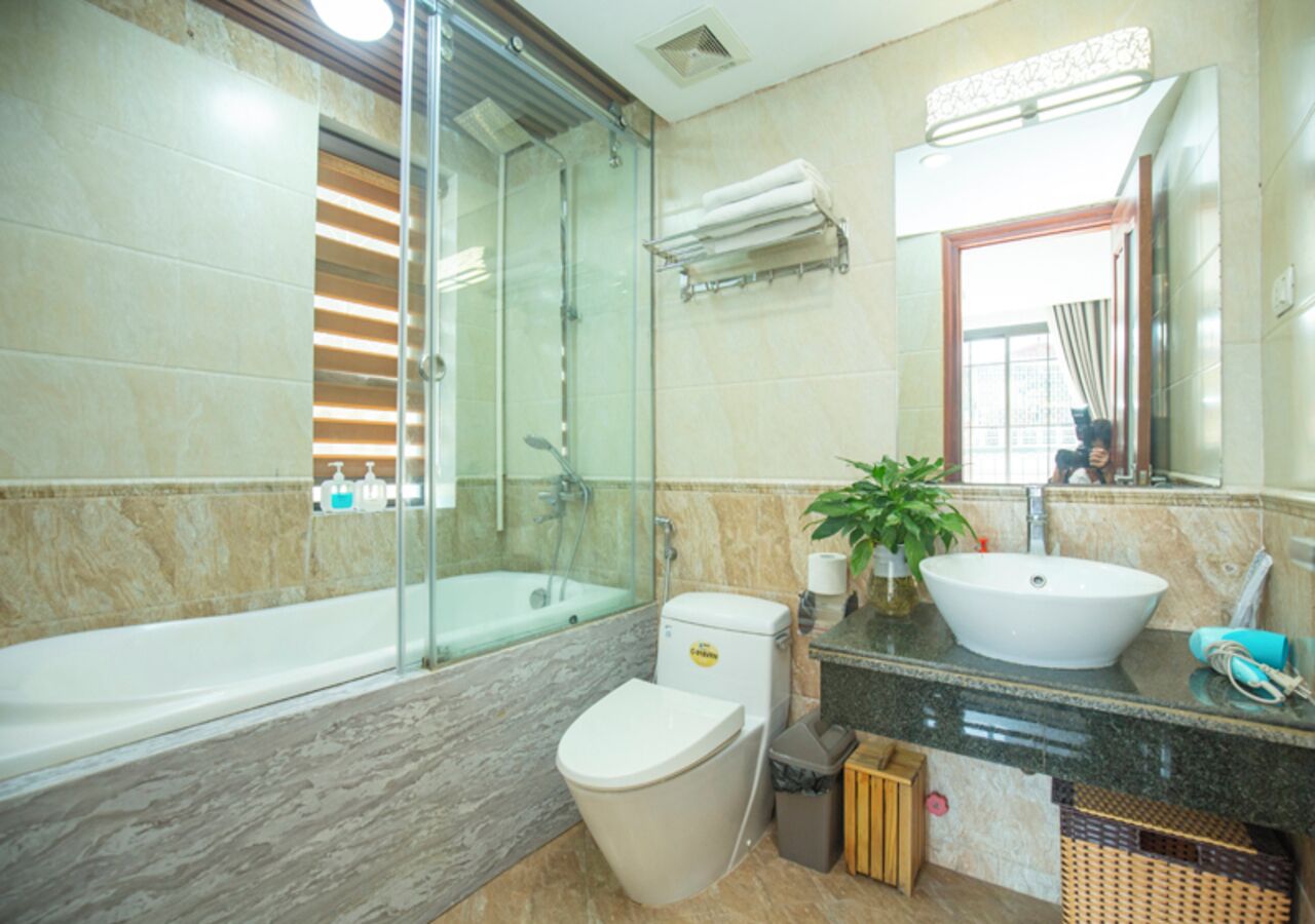 A modern bathroom with a glass-enclosed shower, a bathtub, a toilet, and a sink with a large mirror above it.