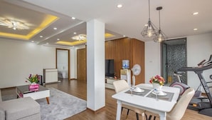 A modern living room with a dining area, a treadmill, and a television in the background. - Sumitomo 2 - 12 Dao Tan (Hanoi)