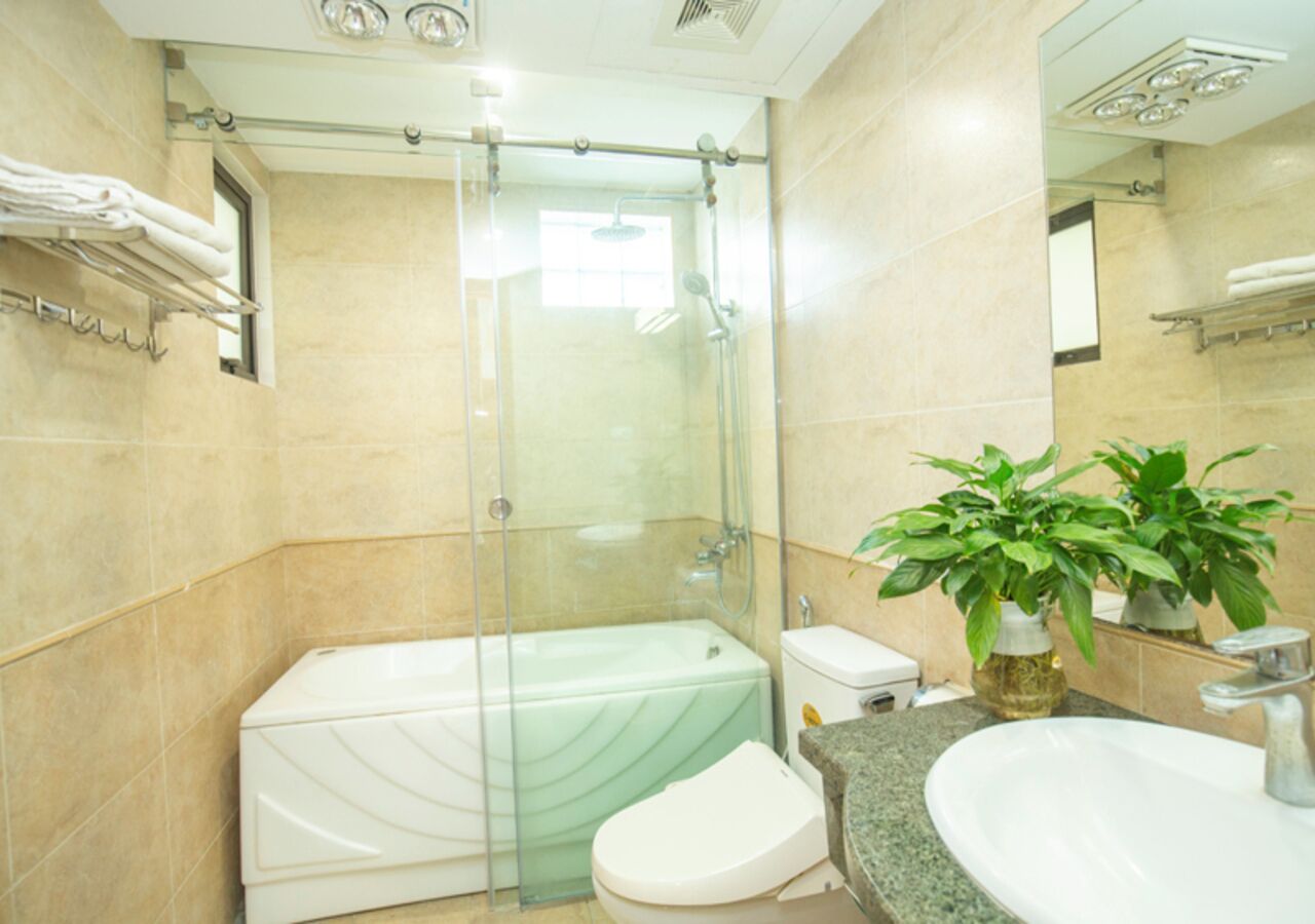 A bathroom with a glass-enclosed shower, a white bathtub, a toilet, and a sink with a granite countertop.
