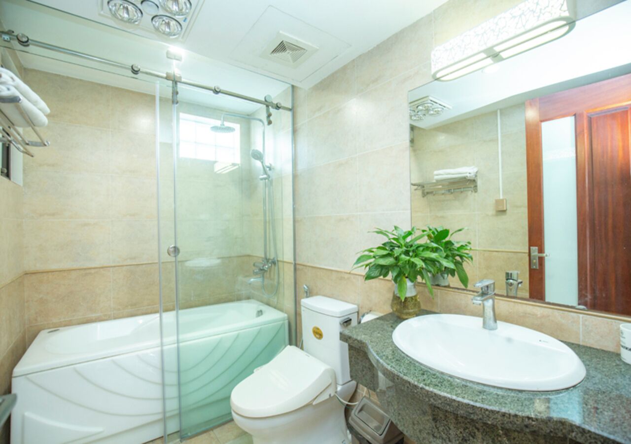 Un baño moderno con ducha de vidrio, inodoro blanco, lavamanos con encimera de granito y espejo.