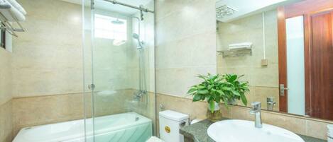 Un baño moderno con ducha de vidrio, inodoro blanco, lavamanos con encimera de granito y espejo.