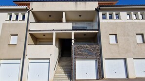A two-story building with a central staircase, two balconies, and two garage doors.