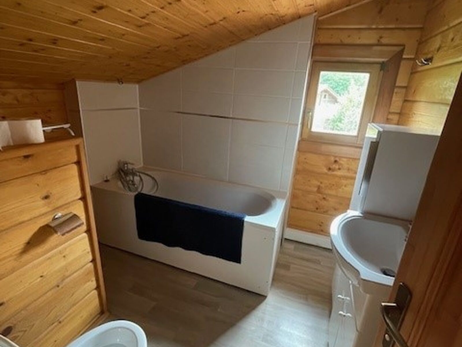 Baño de cabaña de madera con bañera, inodoro y lavamanos.