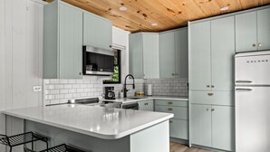 A modern kitchen with white cabinets, a central island, and a built-in oven. - 5 Cabins in GBurg | Sleeps 16 | Firepit & Games (Gatlinburg)