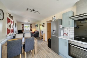 A compact kitchen with a refrigerator, oven, and a dining area with a table and chairs.