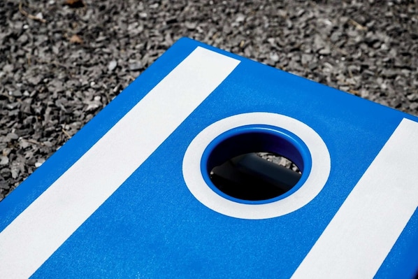 Un objet rayé de bleu et de blanc, avec un trou circulaire, posé sur une surface de gravier.