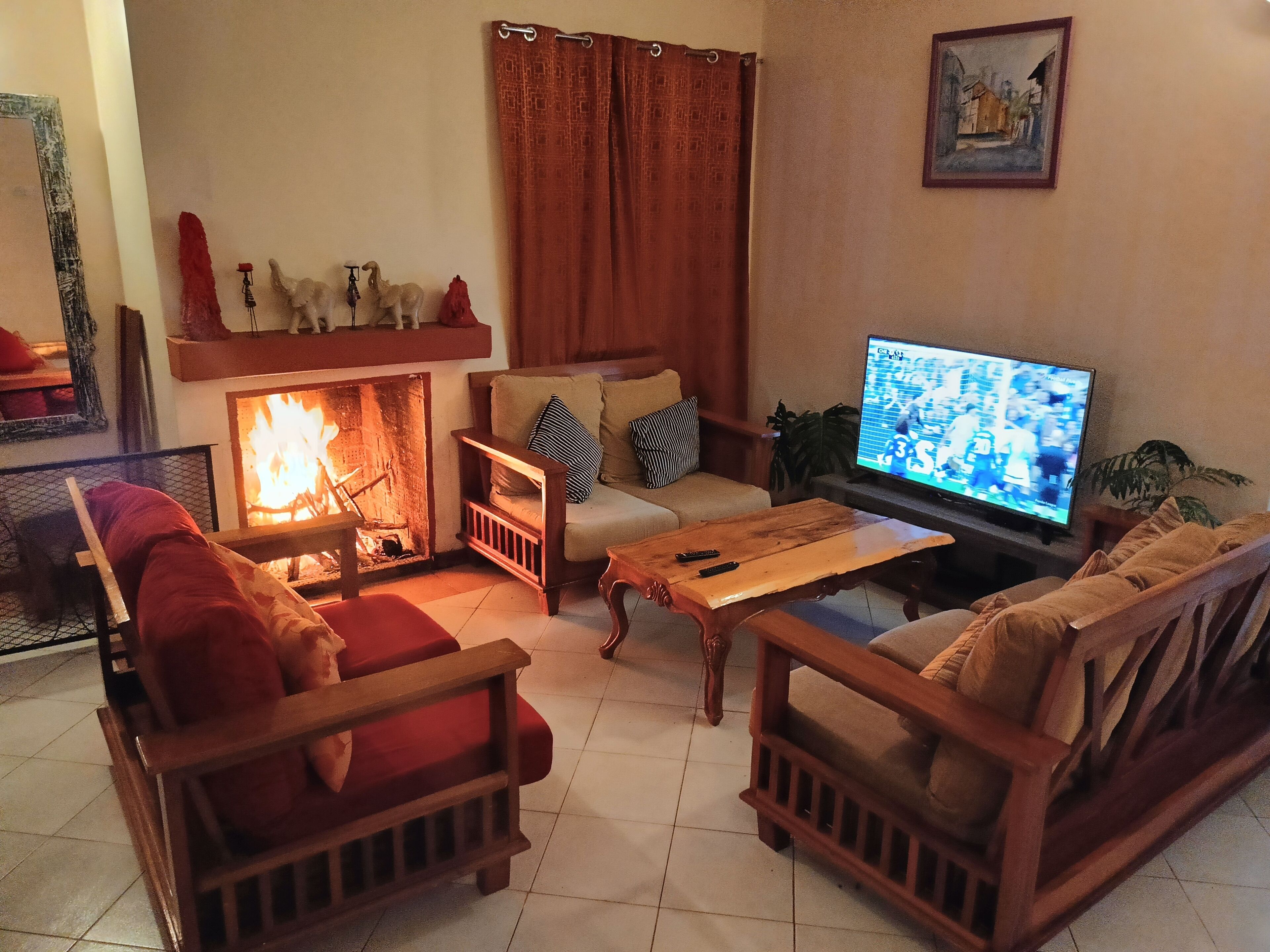 A cozy living room with a fireplace, a sofa set, a coffee table, and a television.