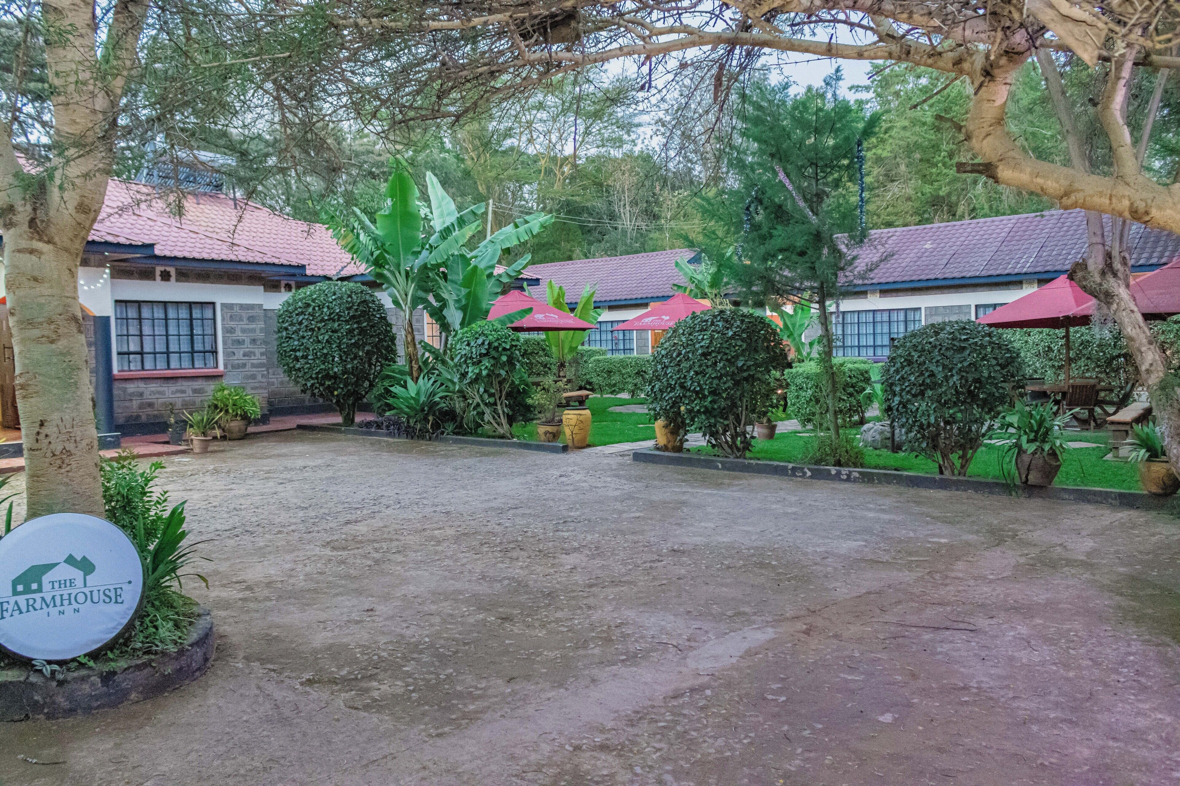 A courtyard with a sign for 'The Farmhouse Inn,' surrounded by potted plants and trees.