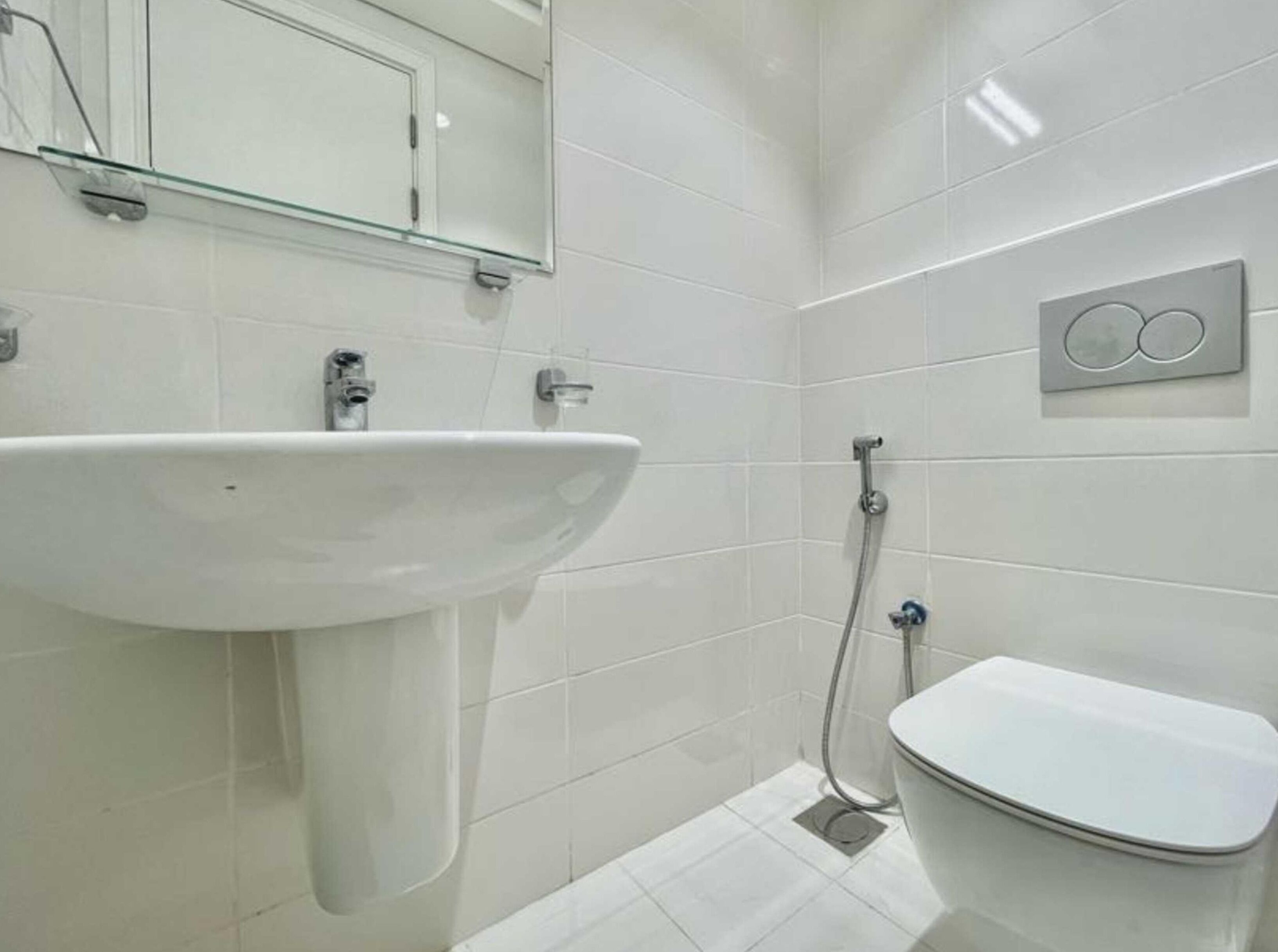 Une salle de bain moderne avec un lavabo blanc, un miroir et des toilettes.