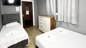 A hotel room with two beds, a TV mounted on the wall, a ceiling fan, and a window with curtains. - HOSTEL ANPRADO (Guarulhos)