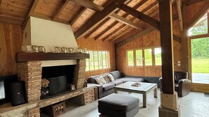 Un vaste espace de vie agrémenté d’une cheminée en pierre, d’un canapé et d’une table basse.