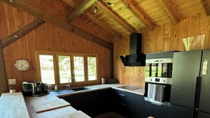 Une cuisine avec des poutres en bois, un poêle noir et un réfrigérateur.