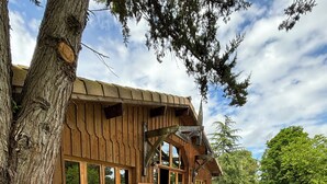 Un bâtiment en bois doté de grandes fenêtres et d’une terrasse en béton.