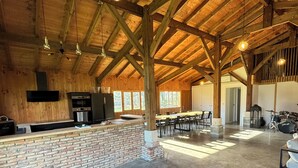 Un vaste espace intérieur doté d’un haut plafond en bois, d’un comptoir en briques et d’un coin salon avec des tables et des chaises.