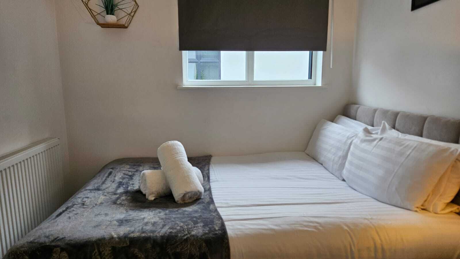 A bedroom with a bed, a window, and a radiator.