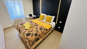 Un dormitori modern amb llit, taula de nit i finestra amb cortines.