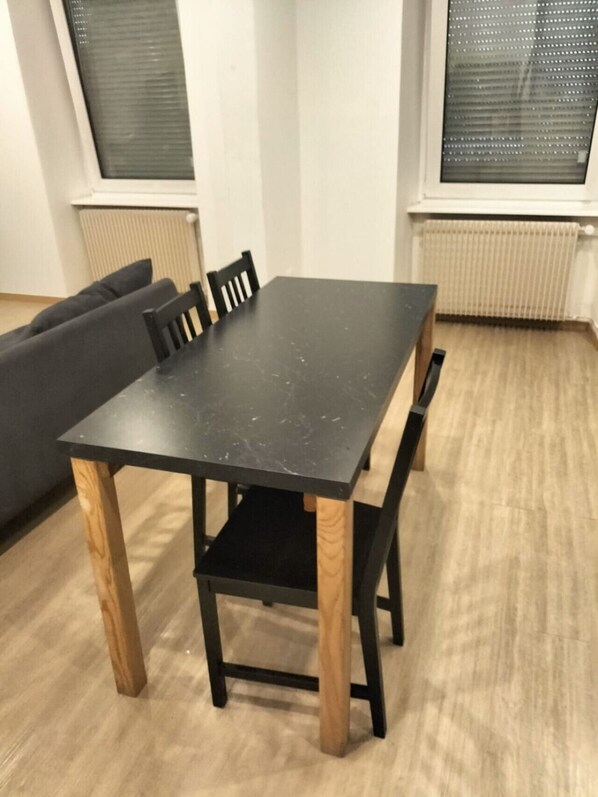 A dining table with four chairs, a black tabletop, and wooden legs.