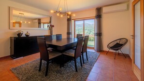 A dining area with a large table, chairs, a chandelier, a mirror, and a view of the outdoors. - Brook House - T3 - Mosteiro, Vieira do Minho (Vieira do Minho)