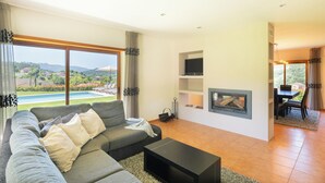 A modern living room with a large sofa, a flat-screen TV, and a fireplace. - Brook House - T3 - Mosteiro, Vieira do Minho (Vieira do Minho)
