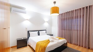 A modern hotel room with a bed, bedside tables, a wardrobe, and a window with curtains. - Brook House - T3 - Mosteiro, Vieira do Minho (Vieira do Minho)