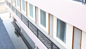 A multi-story building with a white facade, large windows, and a decorative metal railing on the upper level. - Maurya Residency (Gingee)