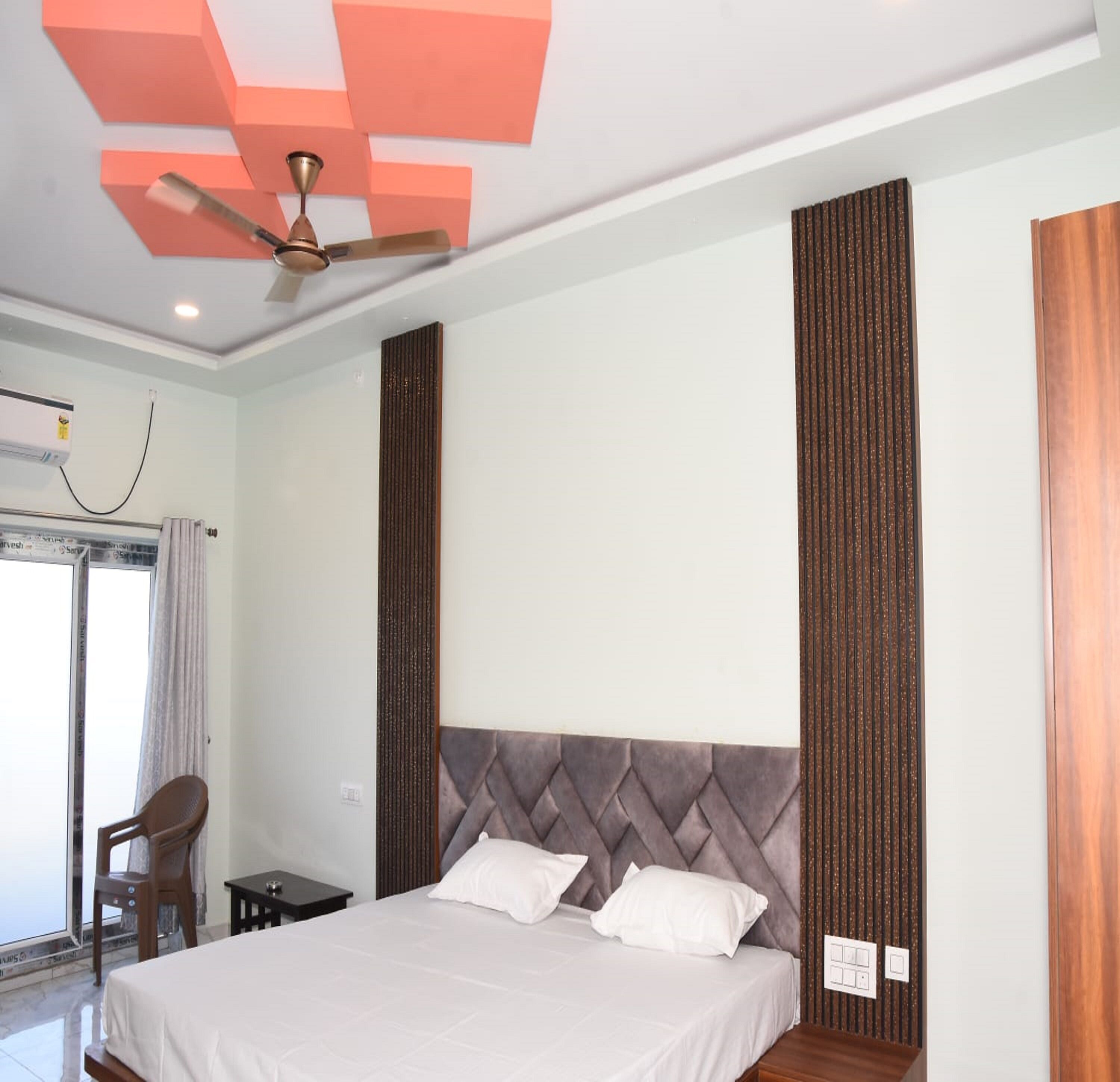 Ein modernes Hotelzimmer mit einem großen Bett, einem Deckenventilator, einem Fenster mit Vorhängen und einem kleinen Tisch.