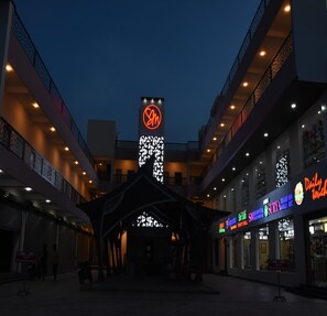 A shopping mall with a prominent 'S' logo sign, multiple levels, and various shops including a visible 'Daily Touch' restaurant. - Maurya Residency (Gingee)
