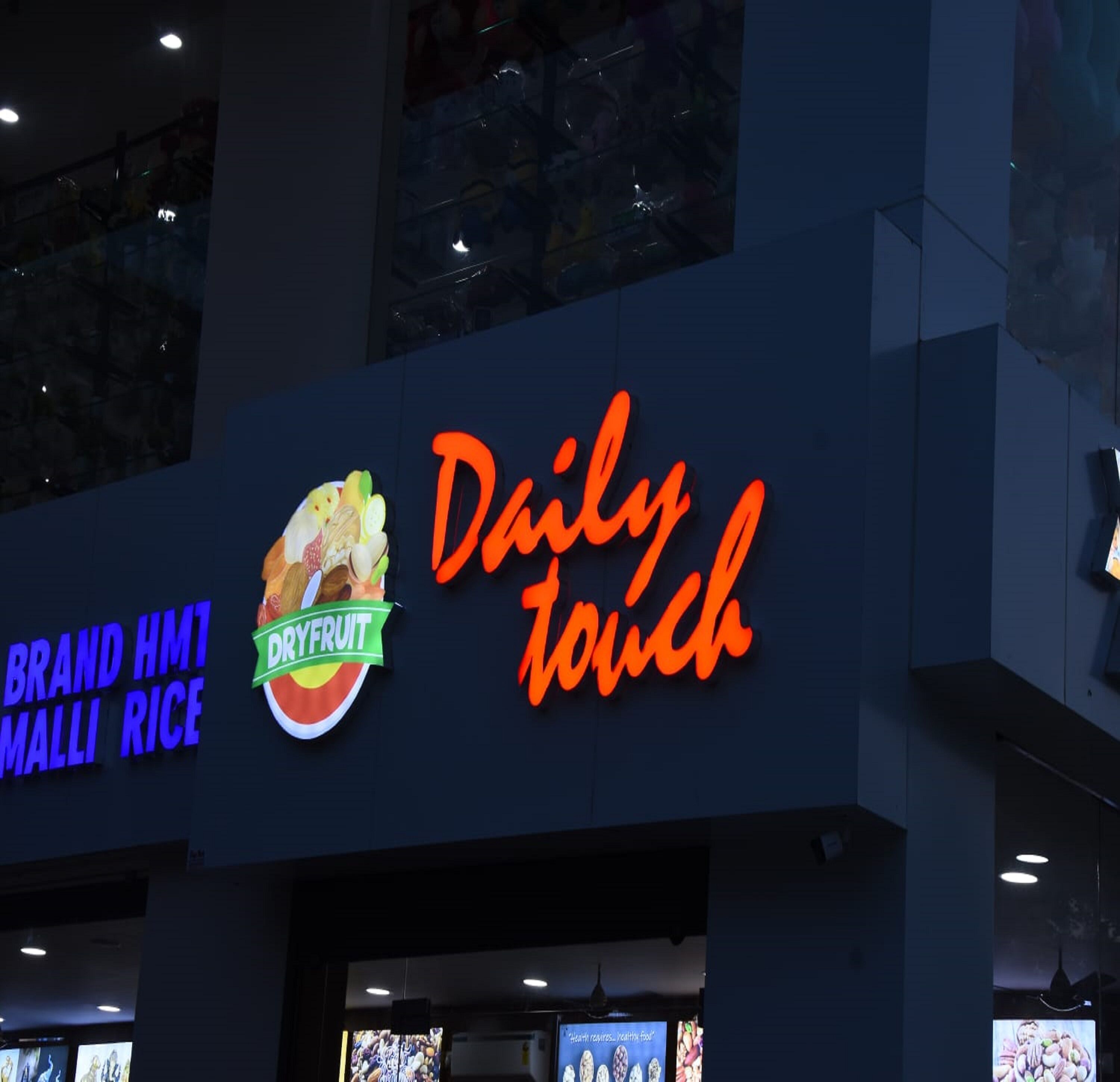 A sign for a food establishment with a neon sign reading "Daily Touch" and a logo for "DryFruit" with a bowl of fruit.