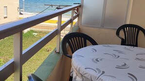 A balcony with a table and chairs, overlooking a beach and sea. - Apartamento muy Fresco Verano (VC)