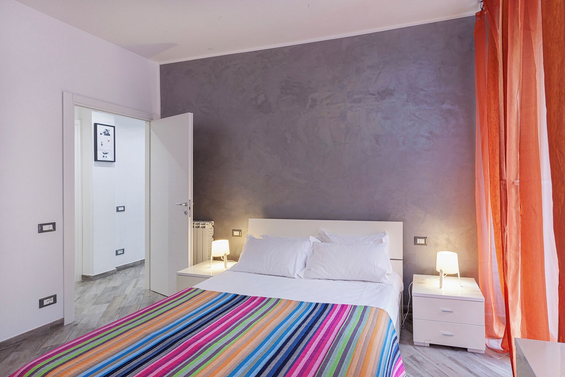 A bedroom with a bed, bedside tables, and a door.