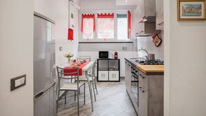 A compact kitchen with a dining area, a microwave, a gas stove, and a small cabinet. - La casa di Lorenzo by Wonderful Italy (Genoa)