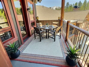 A balcony with a table and chairs, potted plants, and a view of a mountain. - ✨ Seasons at BlueSky - Lux Penthouse 🏔️ Ski In/Ski Out 🎿 Spa 🧖‍♀️Resort Pool (Breckenridge)