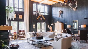 Un salon spacieux doté d’une cheminée, de grandes fenêtres et d’un lustre.