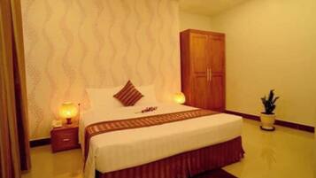 A hotel room with a bed, nightstands, a wardrobe, and a potted plant.