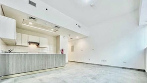 Une cuisine moderne dotée d’un îlot central, de meubles blancs et d’un sol carrelé.