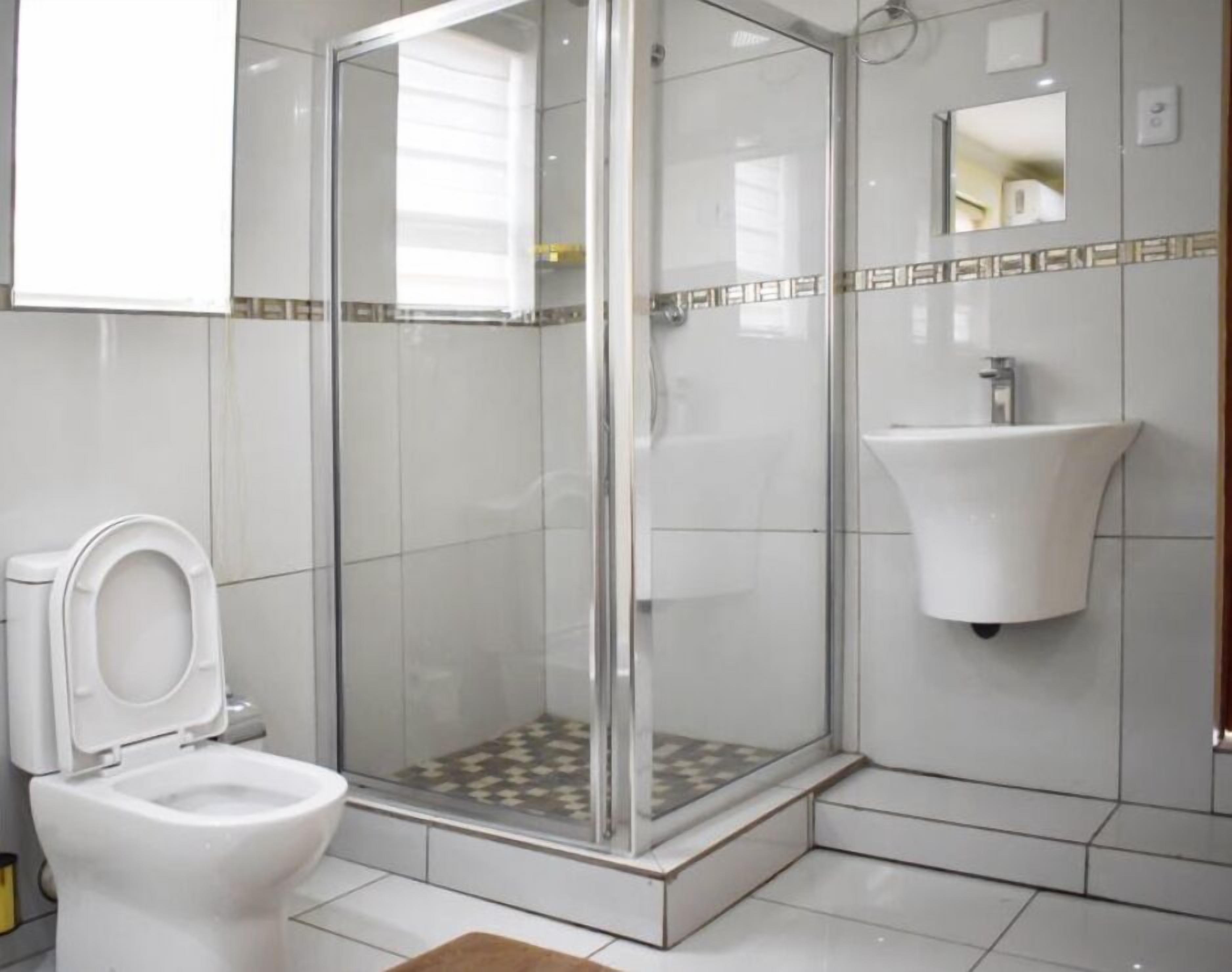 A modern bathroom with a glass-enclosed shower, a white sink, and a toilet.