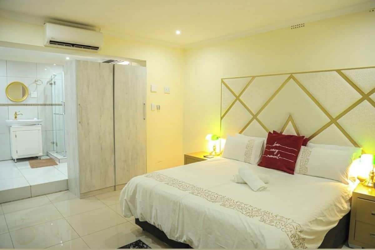 Une chambre d’hôtel comprenant un lit, une table de chevet, une lampe et une salle de bain avec douche et lavabo.