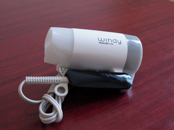 Un secador de pelo portátil blanco y negro con cable enrollado, con la etiqueta 'windy' y 'Tesco 1020'.