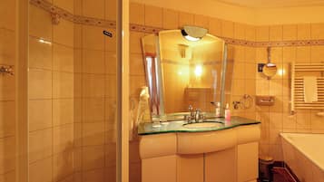 A bathroom with a glass-topped sink, a mirror with a decorative frame, a towel rack, and a shower area.