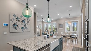 Una cocina con una isla grande, luces colgantes y una zona de comedor con vistas.