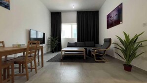 Un salon moderne comprenant un canapé, une table basse, un téléviseur et un coin repas avec des chaises et une table.