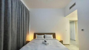 Une chambre d’hôtel avec un lit, une table de chevet, une lampe et une fenêtre avec des rideaux.
