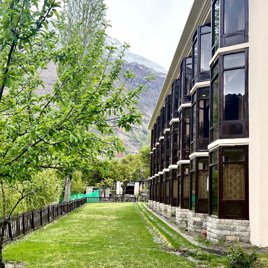 Un hotel con un edificio alargado, ventanas amplias y vistas a una cordillera.