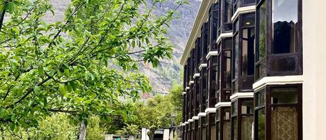 Un hotel con un edificio alargado, ventanas amplias y vistas a una cordillera.