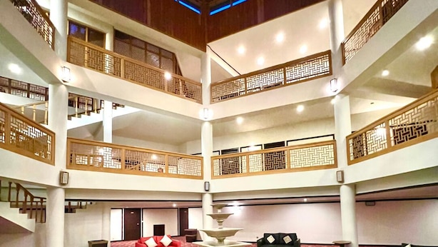 Un hall de hotel de varios niveles con una fuente central, varias zonas de estar y barandillas de madera tradicionales.